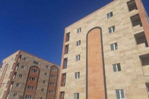 نمای خارجی آپارتمان چندطبقه با سنگ و آجر، پنجرهها و آسمان صاف آبی